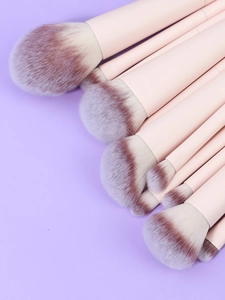 Detail of 12 professional makeup brushes with light pink handles and gradient bristles