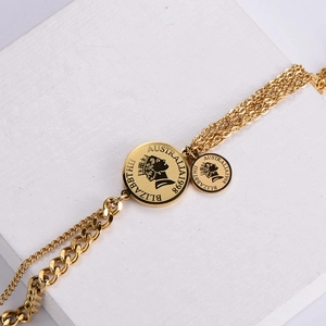 Gold layered chain bracelet with Queen Elizabeth coin pendant on white stone surface