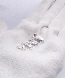 Close-up of five different sizes of S925 sterling silver spring clasps on a white glove