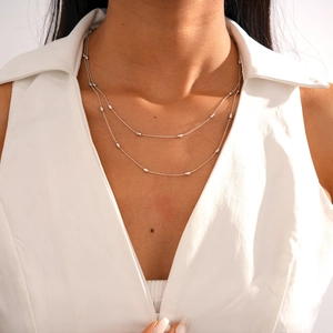 Detail of silver double-layer beaded necklace on a model with white V-neck top