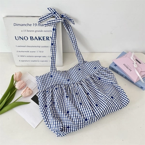 Detail of blue and white gingham pleated tote bag with drawstring bow and soft fabric