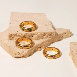 Detailed view of gold plated rings set with green, white and pink zircon on stone props