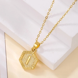 Detail of a gold hexagon pendant with radiant engraving and fine cable chain
