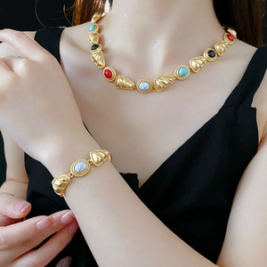 Detail of vintage gold jewelry set with colorful beads on a black garment background