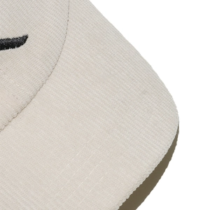 Detailed close-up of ivory corduroy fabric and precise black embroidery on baseball cap