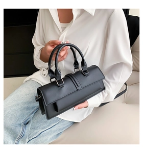 Detail einer schwarzen matten Lederhandtasche mit Doppelgriffen an einem Model