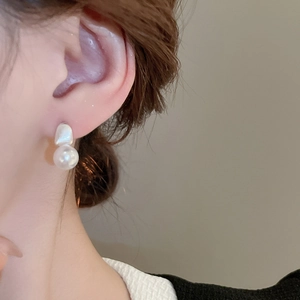 Close-up of elegant irregular silver-toned studs with round faux pearl on a model's ear