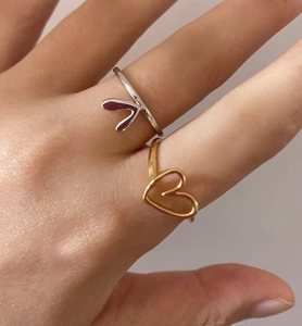 Close-up of minimalist gold and silver heart-shaped metal rings worn by a model
