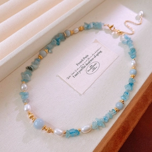 Detailed view of aquamarine stones, freshwater pearls, and golden beads on the necklace