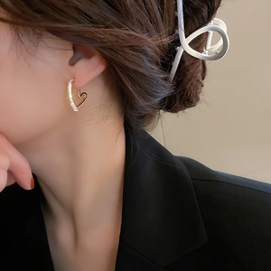 Gros plan d'une boucle d'oreille cœur dorée avec micro-pavage de zircons sur mannequin