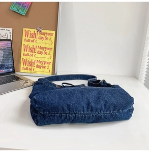 Macro shot of dark blue denim shoulder bag with metal strap buckle on aesthetic desk