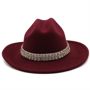 Detail of wool jazz hat with rhinestone-studded silver band on deep red felt material