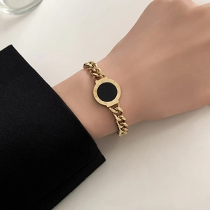 Gold chunky chain bracelet with black circular pendant featuring Roman numeral engravings