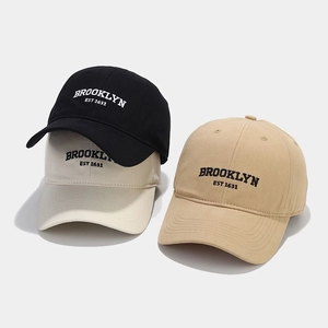 Detail of Brooklyn embroidery on cotton baseball caps in black, cream, and khaki