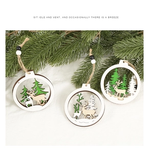 Three hollow wooden Christmas ornaments with reindeer and pine patterns hanging on pine needles