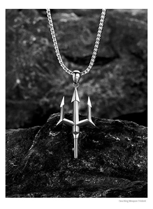 Macro shot of a silver trident pendant with a thick woven chain on a dark textured rock