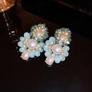 Close-up of flower earrings with blue crystals, pearls, and champagne diamonds
