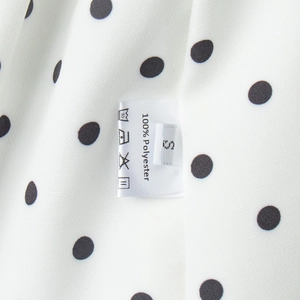 Vue détaillée de l'étiquette 100% polyester et de l'imprimé à pois sur le pantalon