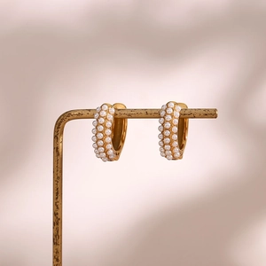 Macro shot of 18K gold plated hoop earrings with rows of pavé set white pearls on a stand