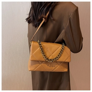 Detail showing the quilted faux leather texture and thick gold chain strap of the caramel bag