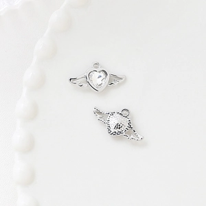 Macro view of silver alloy heart charms with wings and clear cubic zirconia inlays