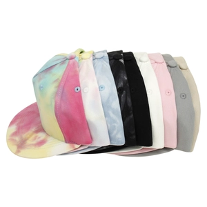 Close-up of assorted tie-dye and solid color hip-hop caps with embroidery and flat brims