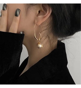 Detailansicht eines geometrischen Goldohrrings mit Perle am Model für Minimalismus