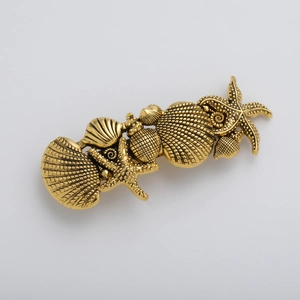 Detail of vintage gold seashell and starfish metal hair clip with embossed textures