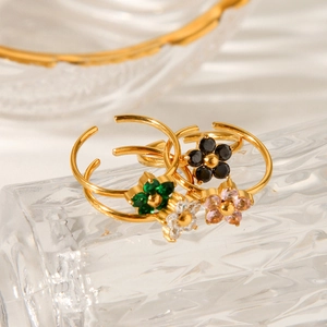 Detailed close-up of gold-plated flower rings with colorful zircon inlays on glass
