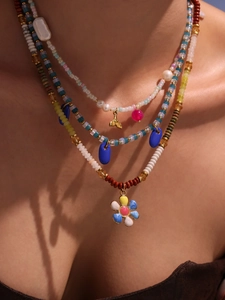 Detail of colorful beaded necklace with floral charm and gold fish tail pendant