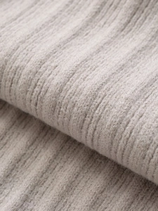 Close-up of soft grey ribbed knit fabric texture on asymmetric belted sweater