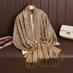 Detail of luxurious brown paisley cashmere scarf with tassels draped over a sofa