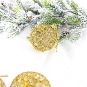 Golden hollow glitter Christmas ball ornament with hanging string on pine branch background