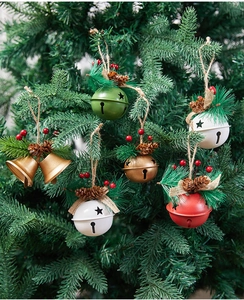 Close-up of metal Christmas bells with pine cones and berries hanging on a pine tree