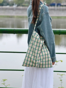 Detail of checkered canvas tote bag in green and purple shown on a model's shoulder
