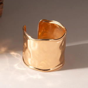 Detail showing the hammered texture and golden metallic finish of the wide cuff bracelet