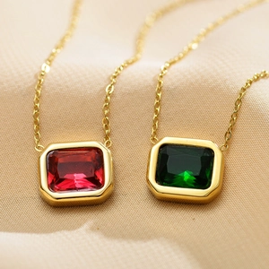 Macro detail of rectangle red and green zircon pendants on minimalist gold chain necklace