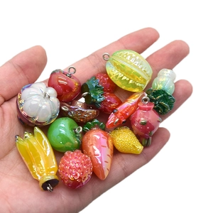 Colorful resin fruit and vegetable pendants held in hand for DIY jewelry making