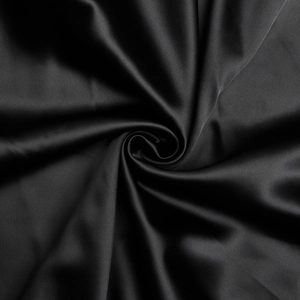 Gros plan du tissu satin noir montrant une texture brillante luxueuse et des plis naturels