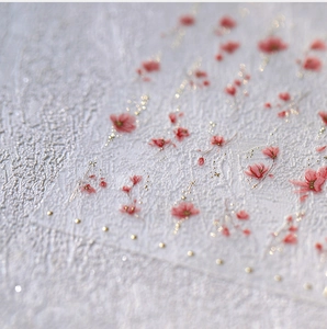 Macro detail of red floral nail stickers with gold glitter and 3D textured matte finish