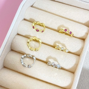 Macro shot of French style gold and silver hoop earrings with zircon in a beige velvet box