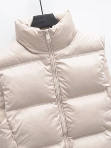 Close-up of cream white puffer vest featuring a high stand collar and quilted texture