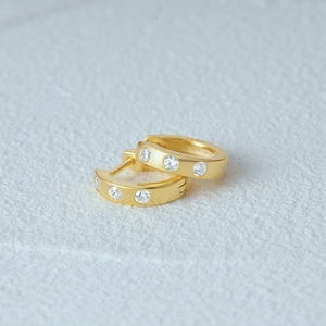 Detail of 18K gold plated S925 silver huggie earrings with three inlaid cubic zirconia