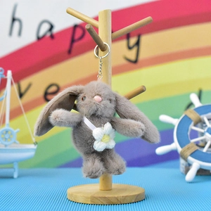 Detailed shot of the cute grey plush rabbit keychain with a white flower accessory