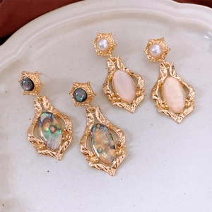 Detailed macro of vintage baroque style earrings with shell inlay and pink stone set in gold