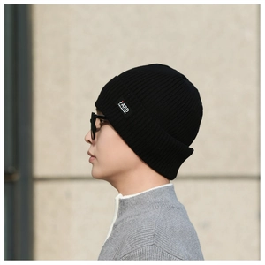 Close-up of a black ribbed knit beanie with a stylish text patch on a side view profile