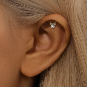 Close-up of gold heart bow earring with sparkling cubic zirconia on a model's ear