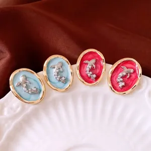 French style oval fish earrings with pearls and gold metal frame on a silk background