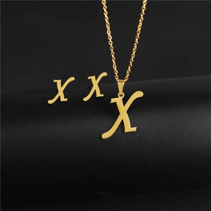 Detailed view of golden letter X pendant necklace and matching stud earrings set