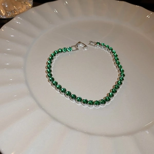 Gros plan de pierres de zircone vert étincelant sur un bracelet de tennis en argent chic